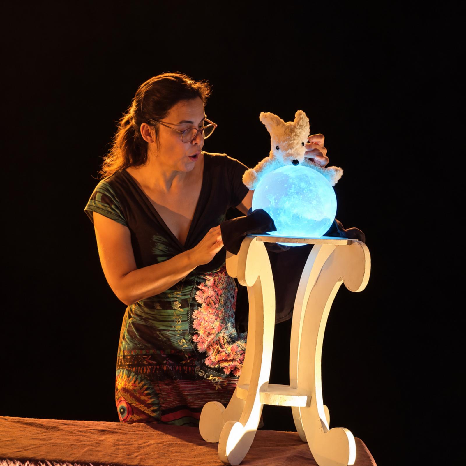 Conteuse avec une lune lumineuse dans le spectacle Quand vient la lune